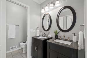 Bathroom featuring toilet, tile patterned flooring, ornamental molding, and vanity