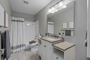 Full bathroom with tile patterned flooring, shower / bath combination with curtain, vanity, and toilet