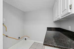 Laundry area with cabinets and light tile patterned floors