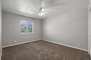 Carpeted empty room featuring ceiling fan