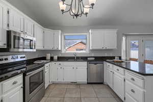 Kitchen featuring appliances with stainless steel finishes, white cabinetry, hanging light fixtures, and sink