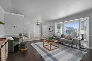 Living room featuring a notable chandelier, crown molding, and wood-type flooring