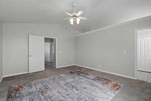 Carpeted empty room featuring lofted ceiling, ceiling fan, and ornamental molding