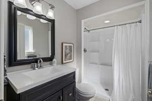 Bathroom with a shower with shower curtain, vanity, and toilet