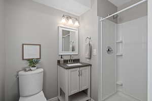 Bathroom featuring toilet, walk in shower, and vanity