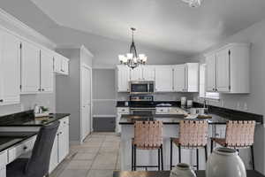 Kitchen with white cabinets, appliances with stainless steel finishes, and vaulted ceiling