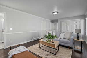 Living room with ornamental molding and dark wood-type flooring