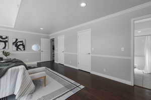 Bedroom featuring ornamental molding, dark wood-type flooring, and connected bathroom