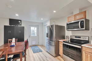 Kitchen with light brown cabinets, light hardwood / wood-style flooring, and appliances with stainless steel finishes