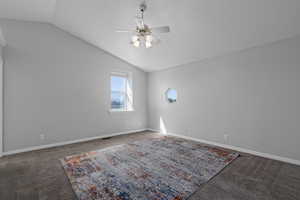 Empty room with lofted ceiling, dark colored carpet, and ceiling fan..this bedroom also en-suite