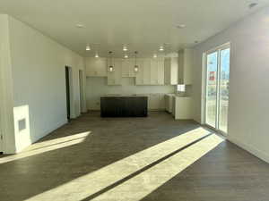 Kitchen featuring a kitchen island, white cabinetry, pendant lighting, and dark wood-type flooring