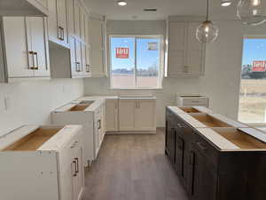 Kitchen with hardwood / wood-style floors, dark brown cabinetry, pendant lighting, and white cabinetry