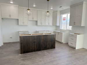 Kitchen featuring a center island, white cabinetry, light hardwood / wood-style flooring, and hanging light fixtures