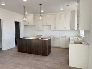 Kitchen with decorative light fixtures, white cabinets, and a center island