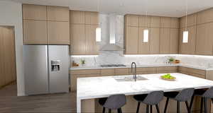 Kitchen with a center island with sink, backsplash, fridge with ice dispenser, wall chimney range hood, and sink