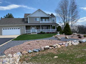 View of front of home featuring a garage, a porch, and a front lawn