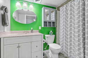 Bathroom with toilet, a textured ceiling, curtained shower, and vanity