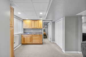 Kitchen featuring light brown cabinetry, light colored carpet, and sink