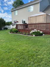 Back of house with a wooden deck and a lawn