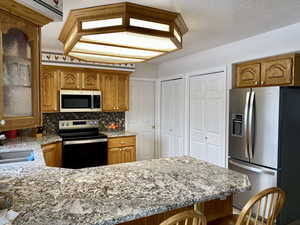 Kitchen featuring tasteful backsplash, stainless steel appliances, a breakfast bar, sink, and kitchen peninsula