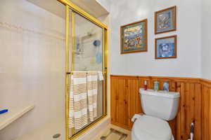 Bathroom with toilet, tile patterned flooring, and a shower with door