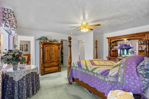 Carpeted bedroom with a textured ceiling and ceiling fan