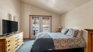 Carpeted bedroom with access to exterior and vaulted ceiling