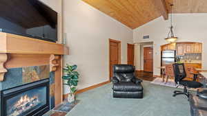Carpeted home office with wooden ceiling, a fireplace, and lofted ceiling with beams