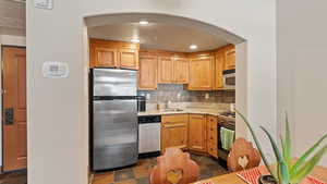 Kitchen with sink, backsplash, and appliances with stainless steel finishes