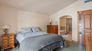 Bedroom with connected bathroom, vaulted ceiling, and tile patterned floors