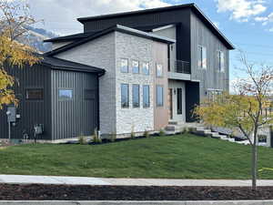 View of side of home with a balcony and a lawn