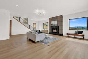 Living room with a tiled fireplace, light hardwood / wood-style floors, and a chandelier