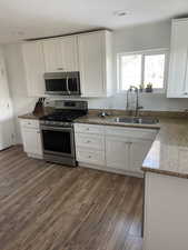 Kitchen with appliances with stainless steel finishes, white cabinets, and sink