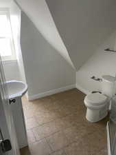 Bathroom with tile patterned flooring, lofted ceiling, vanity, and toilet