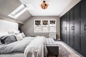 Bedroom featuring a wall mounted AC, a closet, and lofted ceiling with skylight