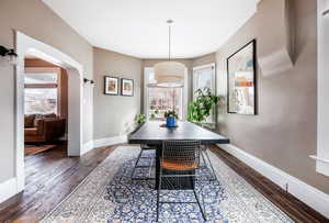 Dining room with a healthy amount of sunlight and dark hardwood / wood-style flooring