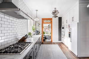 Kitchen with sink, white appliances, gray cabinets, dark hardwood / wood-style flooring, and wall chimney range hood