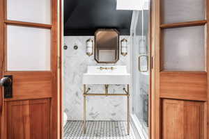 Bathroom with sink, toilet, and a shower with shower door