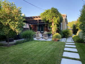 Rear view of property featuring a patio area, a yard, and a pergola