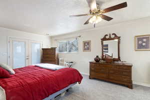 Bedroom featuring ceiling fan, light colored carpet, french doors, and ornamental molding