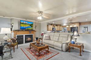 Carpeted living room featuring ceiling fan and ornamental molding