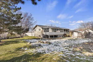 Snow covered back of property with a yard and a sunroom