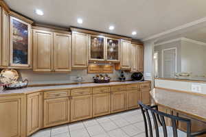 Kitchen with light tile patterned flooring and crown molding