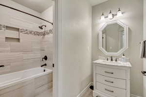 Bathroom with tiled shower / bath combo and vanity