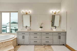 Bathroom with tasteful backsplash, vanity, and tiled bath