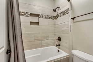 Bathroom with toilet and shower / bath combo with shower curtain