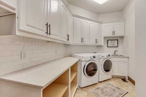 Laundry area featuring sink, cabinets, washing machine and clothes dryer, and light tile patterned flooring