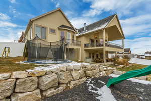 Back of property with a balcony, a playground, and a trampoline