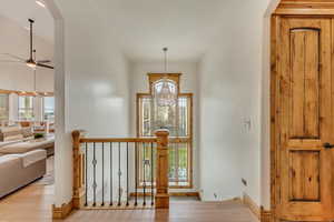 Entryway with ceiling fan with notable chandelier and light wood-type flooring