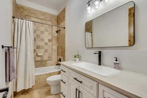 Full bathroom featuring decorative backsplash, shower / bath combo, vanity, and toilet